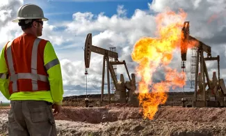 Man standing in front of flaring oil well